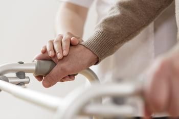 Symbolbild Pflegeberatung: Hände an einem Rollator, darauf werden als liebevolle Geste Hände von Pflegepersonal abgelegt.