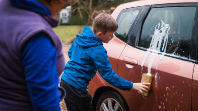 Junge wäscht ein rotes Auto 