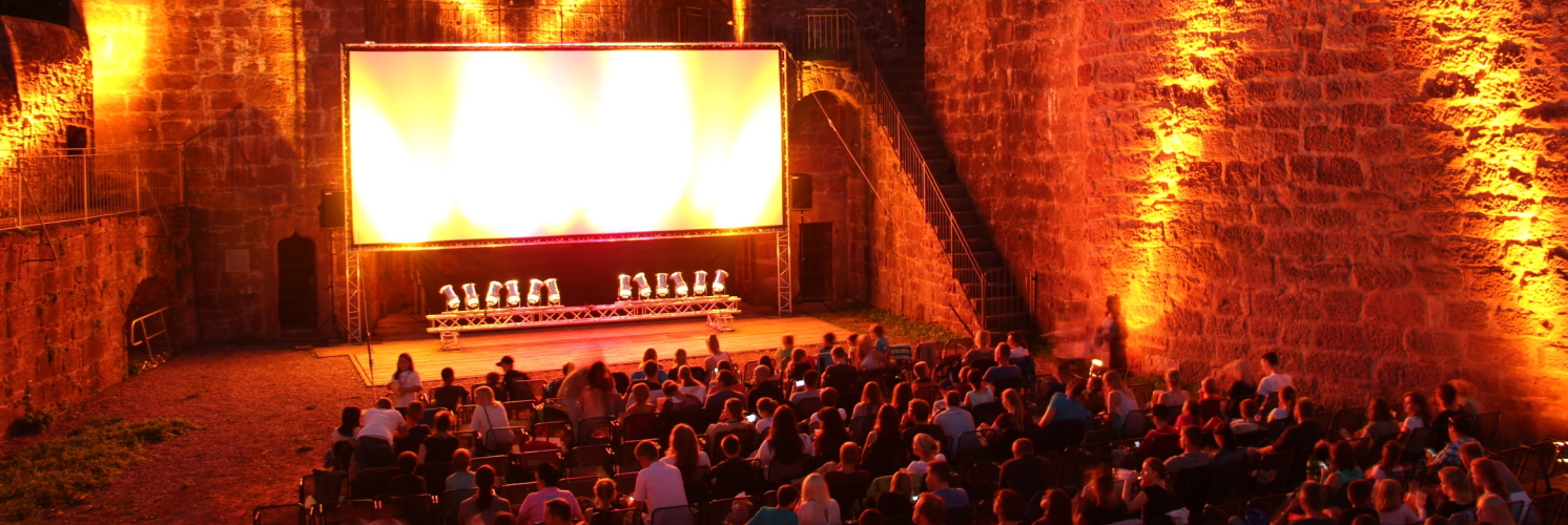 Illuminierter Burggraben mit Publikum vor einer großen Leinwand beim Wertheimer Burgfilmfest